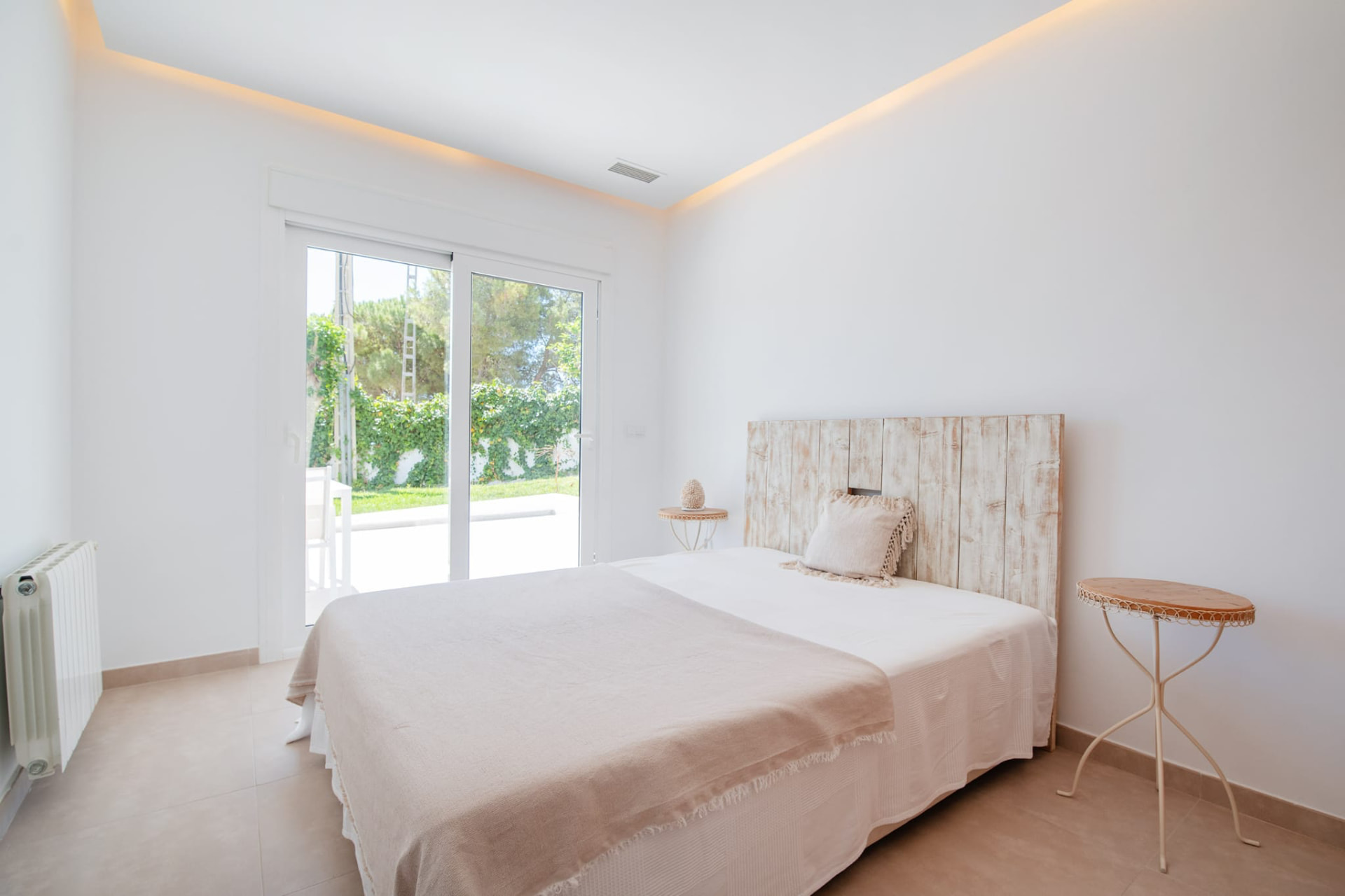 Schlafzimmer mit Holzkopfteil und Gartenblick